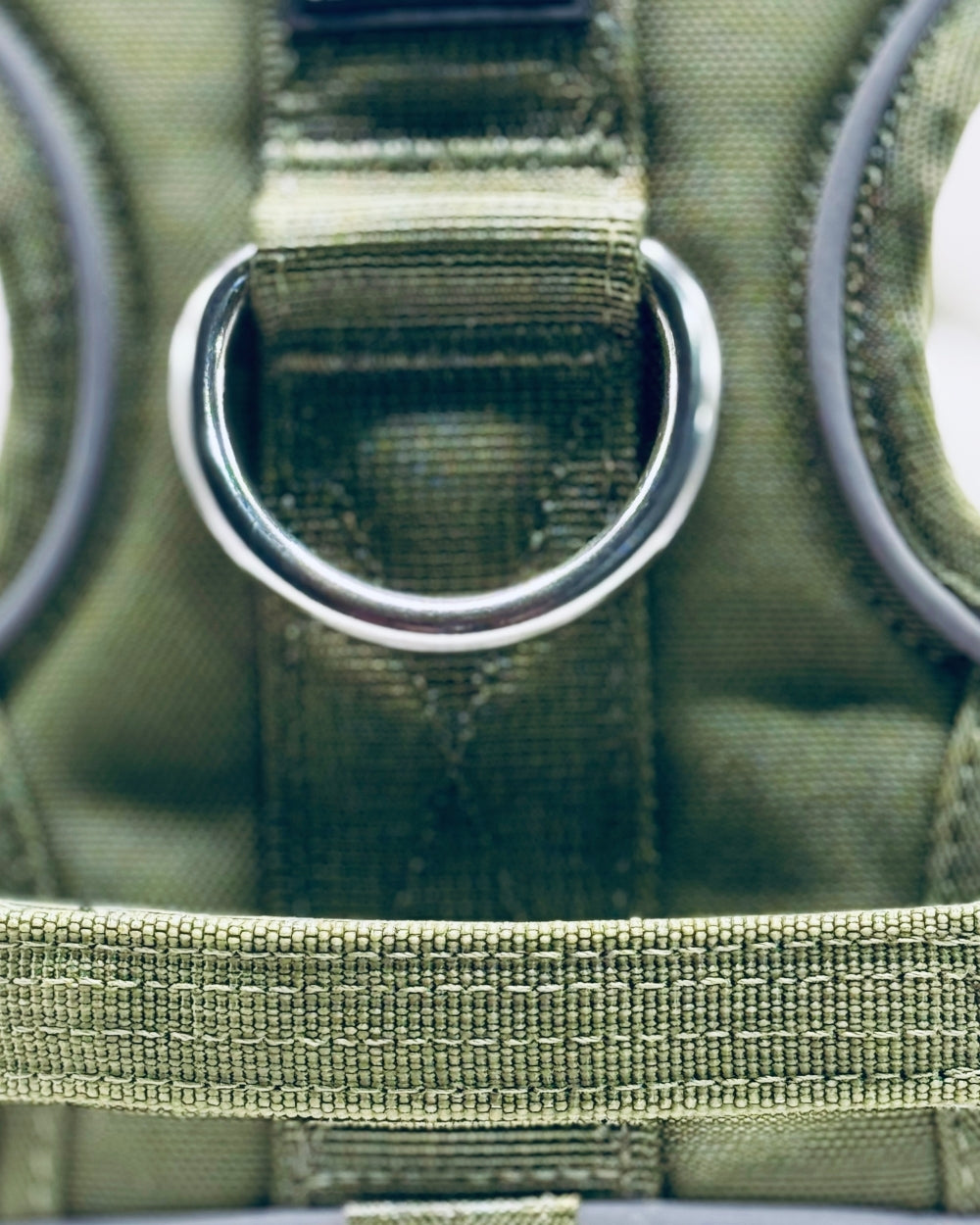 Close-up of a green tactical pouch with a metal D-ring.